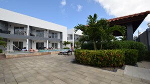 A hotel courtyard with a swimming pool, lounge chairs, and a covered seating area. - Arena Condos Aruba 250 m to Eagle beach Aruba (Noord)
