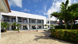 A multi-story hotel with a pool area, outdoor seating, and a well-maintained garden. - Arena Condos Aruba 250 m to Eagle beach Aruba (Noord)