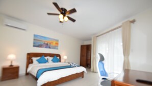A bedroom with a bed, bedside tables, a desk, and a ceiling fan. - Arena Condos Aruba 250 m to Eagle beach Aruba (Noord)