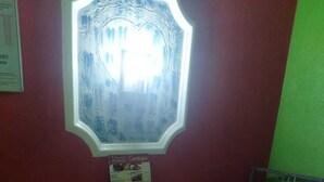 A small dining area with a white table and red chairs, a menu stand, and a decorative wall piece. - Pousada Devaneios (Ananindeua)
