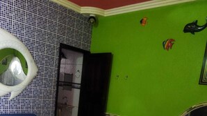 A room with a round bed, a blue sofa, a green wall, and a tiled floor. - Pousada Devaneios (Ananindeua)