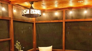 A cozy corner with a wooden ceiling, a table, two chairs, and a vase with a plant. - Cozy Lakefront Bungalow w firepit/dock/kayaks (Plymouth)
