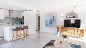 Una cucina moderna con mobili bianchi, un'isola centrale e una zona pranzo con due sedie.