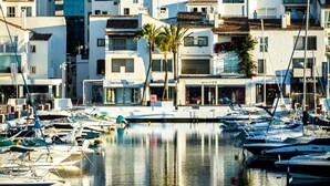 Una marina con barche ormeggiate, un edificio con il cartello 'GUCCI' e una palma.