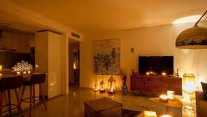 Un soggiorno moderno con zona pranzo, televisore a schermo piatto e illuminazione decorativa.