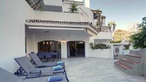 A modern outdoor lounge area with sun loungers and a dining setup.