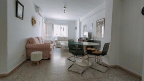 A spacious living room with a glass dining table, two sofas, and a coffee table. - Nerja Sun Apartment Bahía 17 (Nerja)