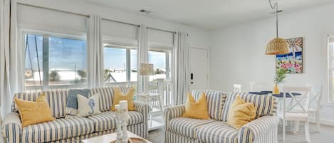 A spacious living room with striped sofas, a white coffee table, and a ceiling fan.