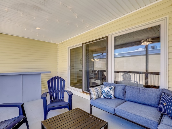 Un patio couvert avec un canapé bleu, une chaise bleue et une table en bois.