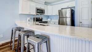 A modern kitchen with white cabinetry, stainless steel appliances, and a marble countertop. - South End Tybee Getaway, Short Walk to Beach (Tybee Island)