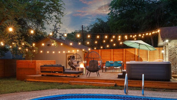 A backyard with a swimming pool, wooden deck, outdoor seating, and string lights. - Pool~Hottub~Yoga Gym~Game Room~Fire Pit (Austin)