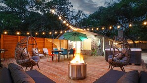 An outdoor patio with a fire pit, wicker chairs, and a table with chairs. - Pool~Hottub~Yoga Gym~Game Room~Fire Pit (Austin)
