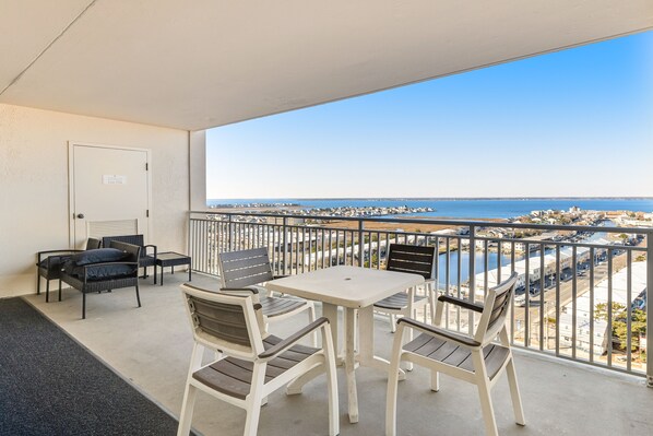 Enjoy the stunning coastal view from this balcony, featuring a table and comfortable seating for six.