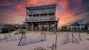 Un hôtel en bord de mer doté de nombreux balcons et d’une plage de sable.