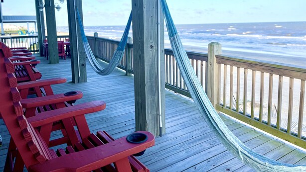 Une terrasse en bois avec des bancs rouges donnant sur l’océan.