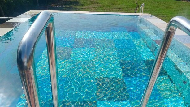 A clear swimming pool with a metal ladder, surrounded by a well-maintained lawn. - Organic Farm with kitchen, AC rooms, Pet-friendly 7 Kms from the city (Jhansi)