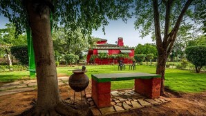 A red building with a tiled roof, surrounded by greenery and trees. - Organic Farm with kitchen, AC rooms, Pet-friendly 7 Kms from the city (Jhansi)
