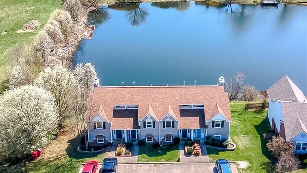 Une grande maison à plusieurs étages, avec une allée centrale et un étang en arrière-plan.