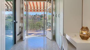 A modern hotel entrance with a glass door leading to a balcony with a view of the city.