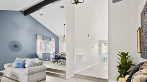 En moderne stue med en grå sofa, spiseområde med stole og en trappe til øvre etage.