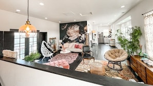 A modern living room with a large floral mural, a dining area, and a kitchen in the background.