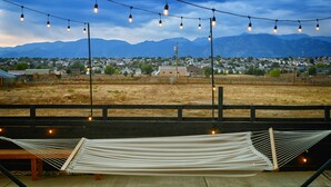 A hammock under string lights with a view of mountains and a town in the background.