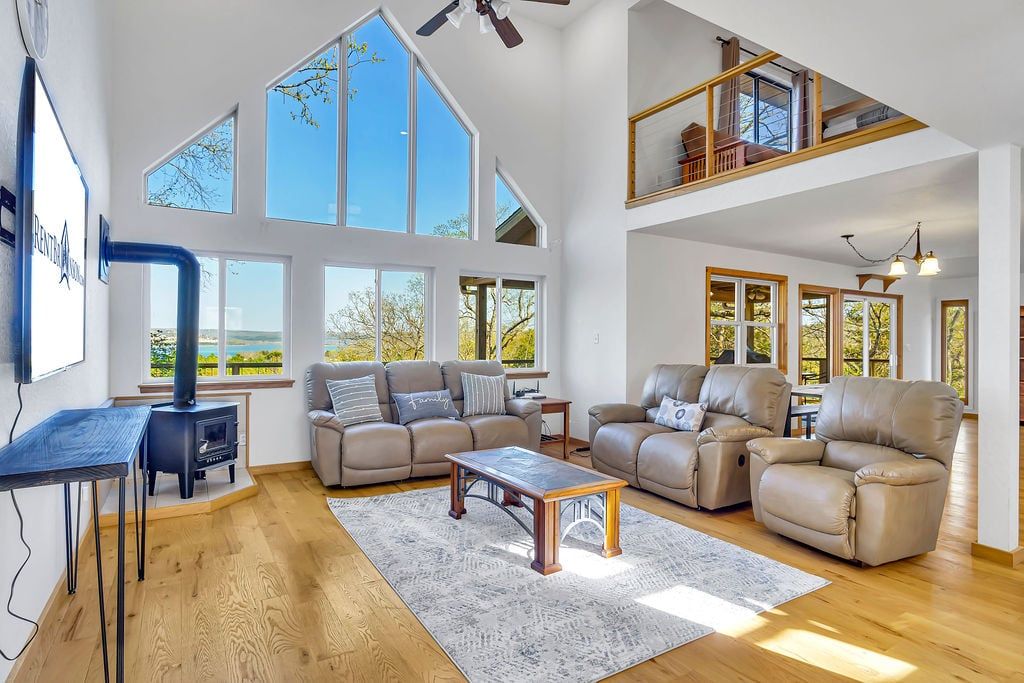 Un salón amplio con techos altos, ventanas grandes y vistas al exterior.