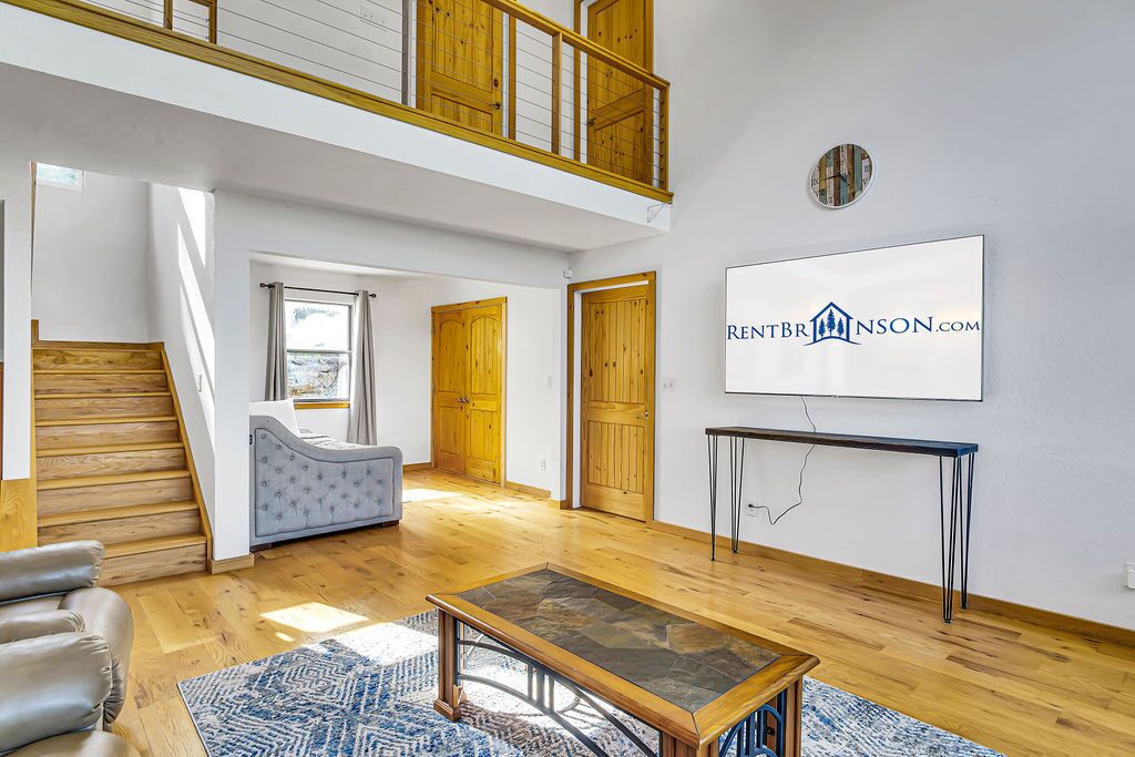 A spacious living area with a staircase, a sofa, a coffee table, and a large window.
