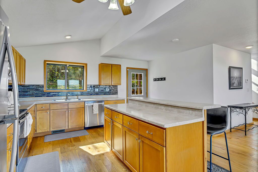 Una cocina moderna con armarios de madera, una isla grande y una zona de comedor con mesa y sillas.