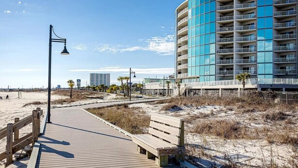 A wooden boardwalk leading to a modern building with balconies. - Top-Floor Condo - On the Beach - Gulf Views - Walk the Boardwalk (Biloxi)