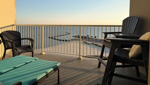 A balcony with a view of the sea, a table, two chairs, and a sunbed. - Top-Floor Condo - On the Beach - Gulf Views - Walk the Boardwalk (Biloxi)