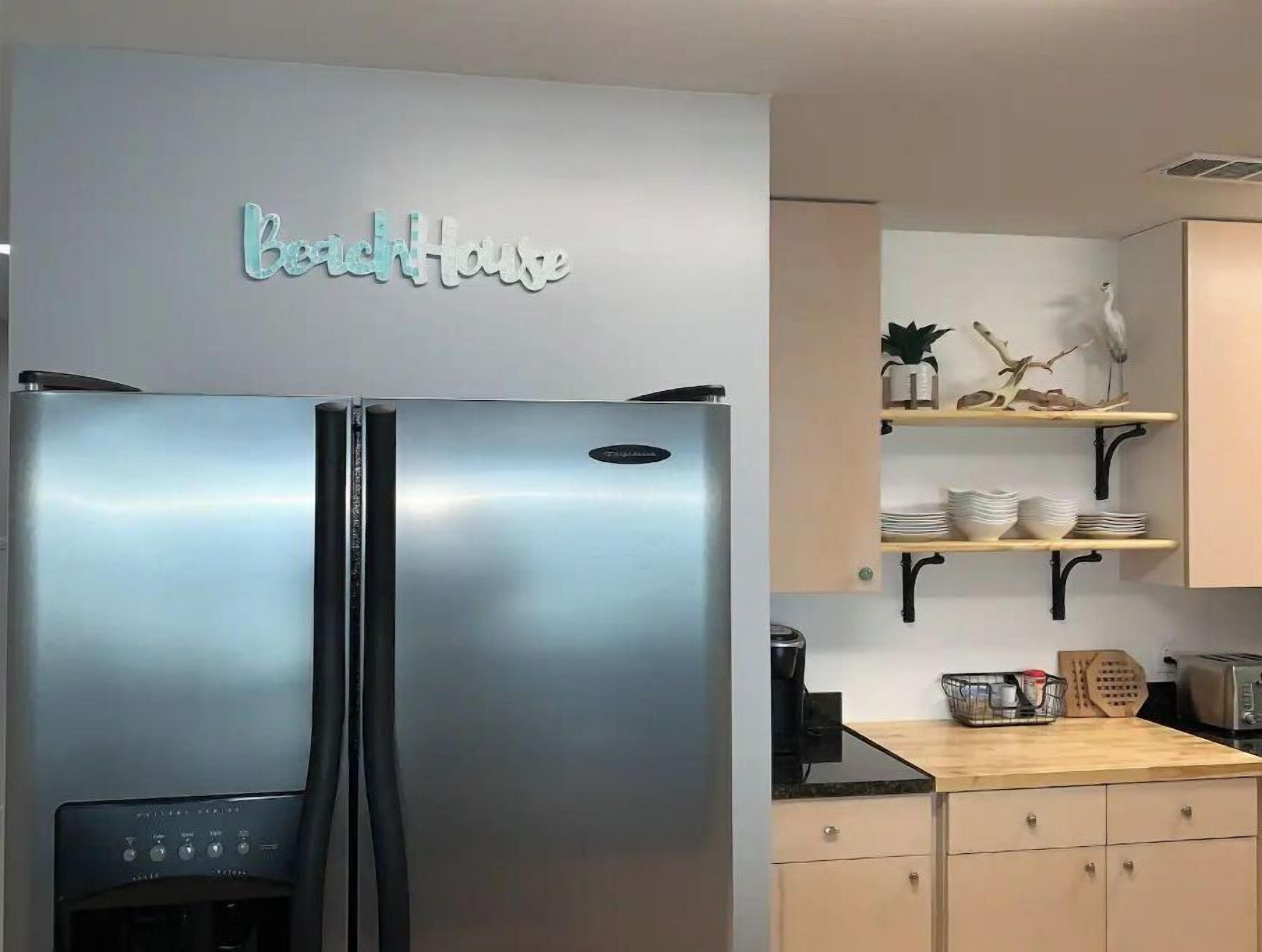 A kitchen with a stainless steel refrigerator, a coffee maker, and a wooden countertop.