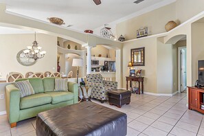 Relax in this stylish living room with a sofa, ottoman, and armchair, perfect for unwinding. Enjoy meals at the dining table and stay entertained with the TV.