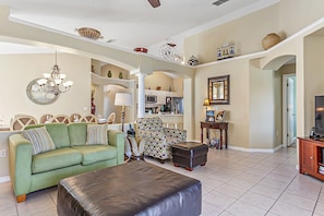 Relax in this stylish living room with a sofa, ottoman, and armchair, perfect for unwinding. Enjoy meals at the dining table and stay entertained with the TV.