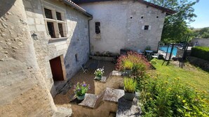 A rustic stone building with a small courtyard, outdoor seating, and a swimming pool. - charming apartment in a 16th century mansion (Allemans)