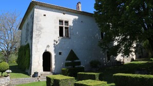 A stone building with a tiled roof, an arched entrance, and a triangular window. - charming apartment in a 16th century mansion (Allemans)