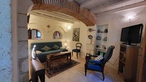 A living room with a green sofa, a wooden coffee table, a blue armchair, a TV stand, and a bookshelf. - charming apartment in a 16th century mansion (Allemans)
