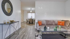 A modern living room with a sofa, coffee table, and a dining area in the background. - Tropical getaway (Santiago De Los Caballeros)