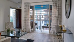 A modern living room with a glass coffee table, patterned cushions, and a view of a balcony with a railing. - Tropical getaway (Santiago De Los Caballeros)