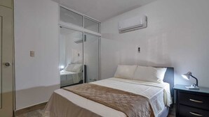A bedroom with a bed, bedside table, and a wardrobe. - Tropical getaway (Santiago De Los Caballeros)