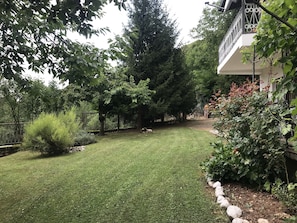 Un jardin bien entretenu, agrémenté de divers arbres et arbustes, d’un chemin en pierre et d’une zone délimitée par une clôture.