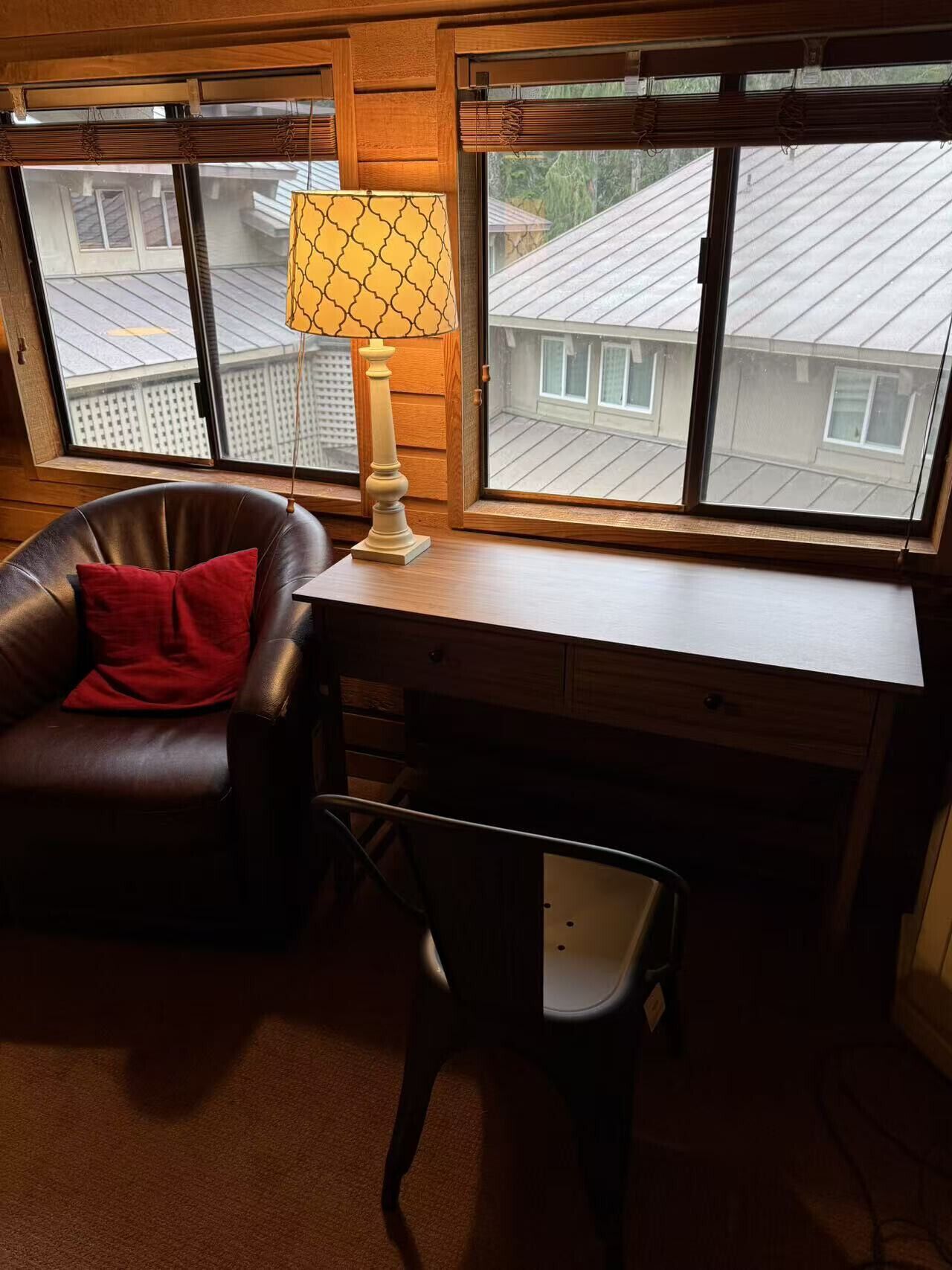 Una habitación acogedora con una butaca de cuero, un escritorio y una lámpara.