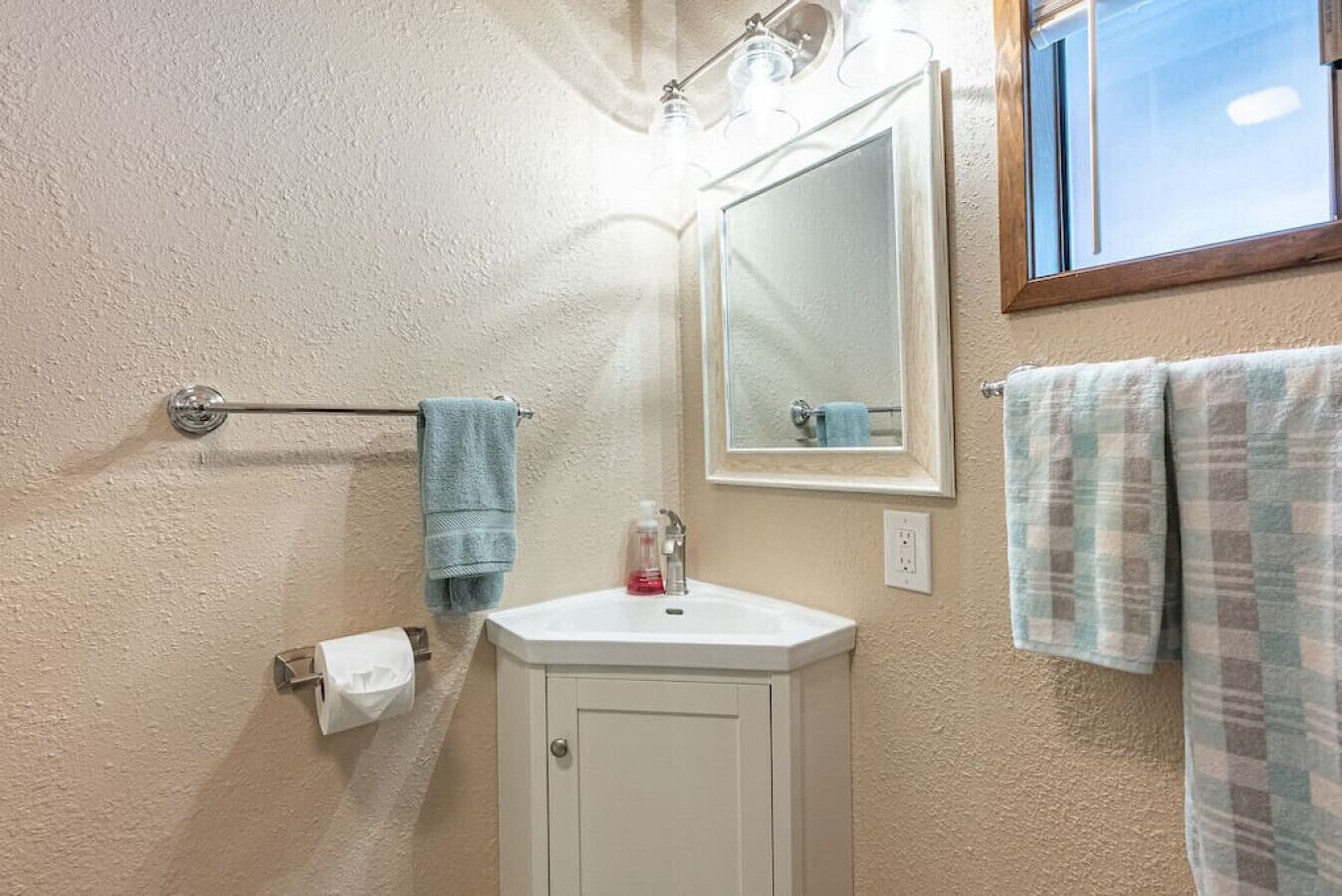 A bathroom with a white sink, a mirror, and two towels hanging on the wall.