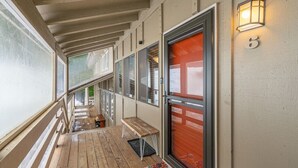 A covered porch with wooden railings, a bench, and a welcome mat.