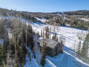 A snow-covered ski resort with a lodge in the foreground and ski slopes in the background.