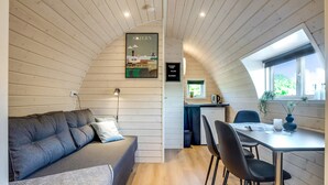 Una habitación acogedora con sofá, una mesa de comedor con sillas, una pequeña cocina y un ventanal con vistas.