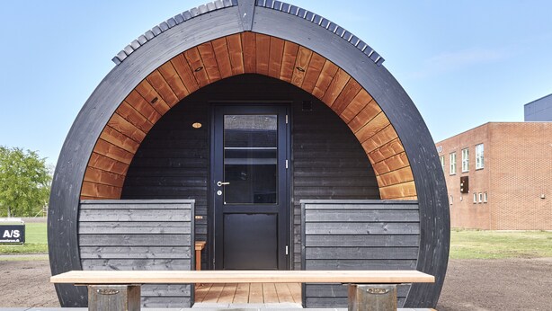 Una estructura moderna de arco con un banco de madera al frente.