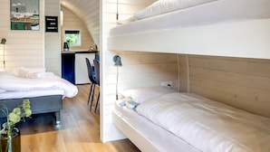 Una habitación moderna y compacta con literas, un pequeño rincón de cocina y un comedor.