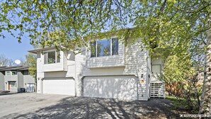 Ein zweistöckiges Haus mit Garage, Satellitenschüssel und einer kleinen Veranda.