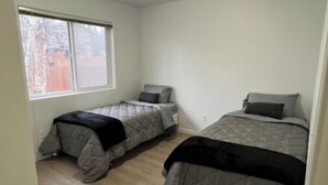 Un dormitorio con dos camas, una ventana y una lámpara en el techo.